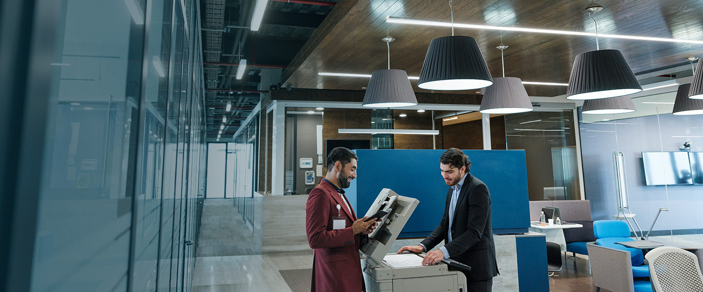 Two people having a discussion by a printer.